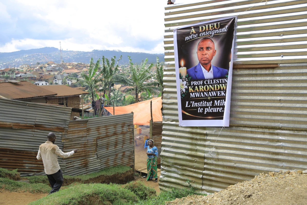 Mourners gather near a banner honoring Marie-Célestin Karondwa in Butembo